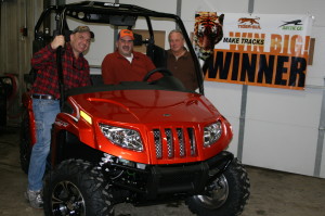 Drew Taylor (L) and John Myers (R) of H.J. Baker’s Tiger-Sul Products present Kevin Dockter (C) with a new Arctic Cat Prowler ATV as the Grand Prize winner of the “Make Tracks Win Big” sweepstakes.